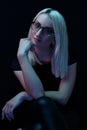 Pensive young Caucasian beautiful blonde woman with glasses . close-up portrait in neon light Royalty Free Stock Photo