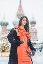 Caucasian girl in a red dress holds in hand an accordion in the winter background of St. Basil`s Cathedral Royalty Free Stock Photo