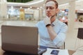 Pensive young Caucasian man sit at table food court work online on laptop pondering thinking Royalty Free Stock Photo