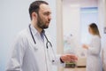 Pensive young doctor in white coat holding diagnosis in hospital, caring doctor concept