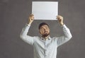 Pensive young man hold white mockup paper sheet