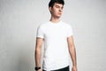Pensive young man wearing blank white t-shirt, horizontal studio