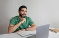 Pensive young muslim man student, manager making notes, planning day at laptop, create idea Royalty Free Stock Photo