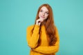 Pensive young redhead woman girl in yellow sweater posing isolated on blue turquoise background studio portrait. People Royalty Free Stock Photo