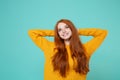 Pensive young redhead woman girl in yellow sweater posing isolated on blue turquoise wall background studio portrait Royalty Free Stock Photo
