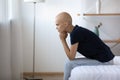 Pensive young woman with bald head ponder on cancer treatment