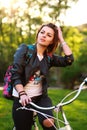 Pensive young woman on bicycle in green park on sunset Royalty Free Stock Photo