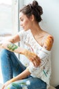 Pensive young woman dirty with paints looking at the window