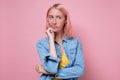Pensive young woman with dyed pink hair looking aside