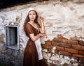 Pensive young woman in a rustic dress standing near old brick wall in old house feel lonely. Cinderella style Royalty Free Stock Photo