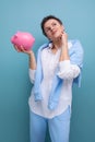 a pensive young woman with a short haircut holds a piggy bank and thinks where to invest the accumulated money Royalty Free Stock Photo