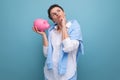 a pensive young woman with a short haircut holds a piggy bank and thinks where to invest the accumulated money Royalty Free Stock Photo