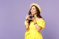 Pensive young woman in yellow dress hat taking pictures on retro vintage photo camera looking aside isolated on pastel Royalty Free Stock Photo