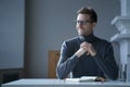 Pensively smiling male entrepreneur sitting at table in front of open agenda with folded hands Royalty Free Stock Photo