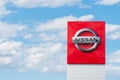 Nissan logo on sign outside car dealership with blue sky in background
