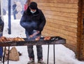 A masked man prepares a barbecue in the fresh air
