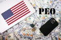 PEO. Professional Employer Organization concept. USA flag, dollar money with keys, laptop and phone background