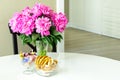 Peonies in a glass vase,sweets and bagels on a white round table.