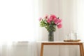 Peonies in vase and tray with jug and glasses of water on console table near wall. Room interior Royalty Free Stock Photo