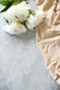 Peony flowers and beige cloth on grey stone background. Vertical greeting card mockup for birthday, Mother`s Day, Woman`s day,