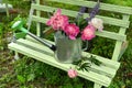 Peony and lupine flowers in watering can on bench in the garden Royalty Free Stock Photo