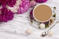 Peony and sweets teacup and spoon on white wooden table.