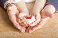 People, age, family, love and health care concept - close up of senior woman and little boy hands holding red heart over wooden Royalty Free Stock Photo