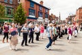 People of all ages line dancing in the street.