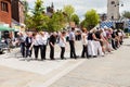 People of all ages line dancing in the street.