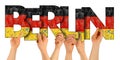 People arms hands holding up wooden letter lettering forming word Berlin capital city of germany in german national flag colors