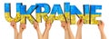 People arms hands holding up wooden letter lettering forming word UKRAINE in ukrainian national flag colors  blue and yellow. war Royalty Free Stock Photo