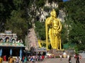 People around the large golden sculpture of Murugan at the base of the Batu Caves stairs. Malaysia