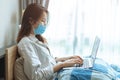 People Asian girl teen Coronavirus flu infected working at home by laptop computer online wear protective disposal face mask