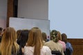 People in auditory during presentation or seminar. Teenagers or young men and women at university lecture or seminar. Back side