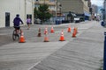 People avoiding orange hazard cones marking damaged wooden planks on a wooden boardwalk