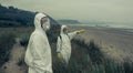 People in bacteriological protective suits watching the sea Royalty Free Stock Photo