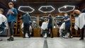 People at barbershop. Team of professional barbers working with clients in the modern loft style barber shop. General