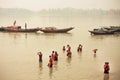 People bathing in dirty water of indian river past the riverboats