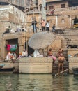 People Bathing next to funeral pyres on the edge of the Ganges River in Varanasi, India