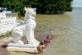 People bathing and washing on the riverbank of Irrawaddy River, next to chinthe statues, Burma