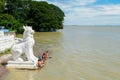 People bathing and washing on the riverbank of Irrawaddy River, next to chinthe statues, Burma