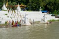 People bathing and washing on the riverbank of Irrawaddy River, next to chinthe statues, Burma