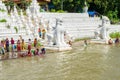 People bathing and washing on the riverbank of Irrawaddy River, next to chinthe statues, Burma