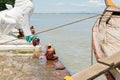 People bathing and washing on the riverbank of Irrawaddy River, next to chinthe statues, Burma