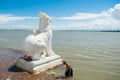 People bathing and washing on the riverbank of Irrawaddy River, next to chinthe statues, Burma