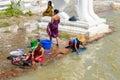 People bathing and washing on the riverbank of Irrawaddy River, next to chinthe statues, Burma