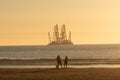 People at beach looking at industrial barge off Dutch coast Royalty Free Stock Photo