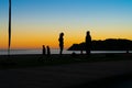 People on beach at Mount Maunganui at sunrise in silhouette doing morning fitnes exercise and walking by