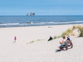 People on beach and North Sea with offshore platform, West Frisian island Ameland, Friesland, Netherlands