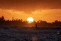 young male tourist runs along the beach. Silhouette of a joyful, happy tourist against a beautiful sunset on a tropical island. Royalty Free Stock Photo